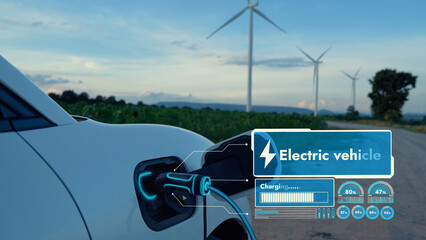 Electric car recharging energy from EV charging station display futuristic smart battery status hologram by EV charger plug cable in wind turbine farm. Alternative clean energy sustainability. Peruse