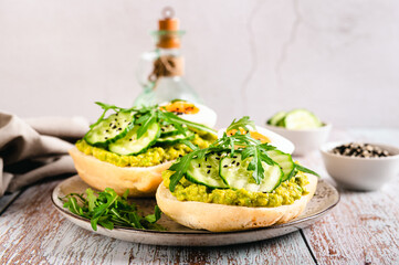 Sandwiches on ciabatta with avocado, cucumber, egg and arugula on a plate