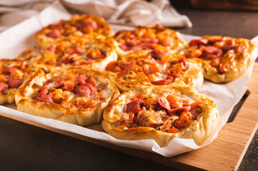 Fresh pizza pot pies with tomatoes, cheese and sausages on a wooden board