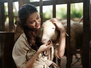 A woman in a white dress petting a sheep in a fenced in pen