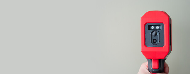 Close up man holds a thermographic camera. Device for monitoring the temperature distribution of the surface under study. thermal imager in hand. Infrared thermography. A place for the text.