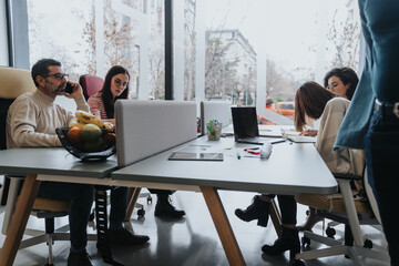 Various generation coworkers discussing strategies, working as a team to ensure their startup's success in a modern office.