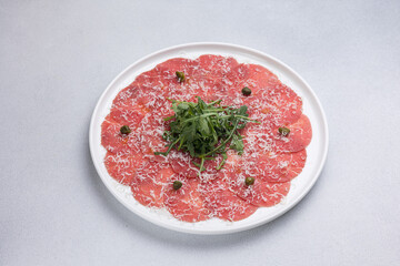 Fresh carpaccio with veal and arugula on a round plate