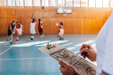 Close up of senior coach's hands writing game plan on basketball training.