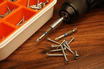 Screws and screw gun on a wooden table. High quality photo
