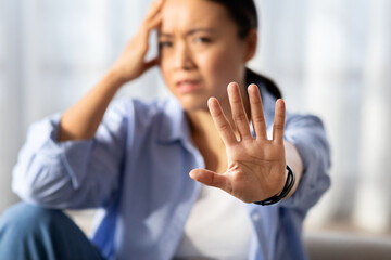 Asian woman showing stop gesture, home interior