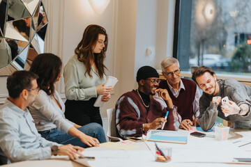 A group of diverse colleagues engage in a creative brainstorming session in a well-lit, casual office setting with smart phones, notes, and warm interaction.