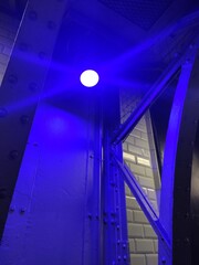 Petite lumière bleue éclairant une structure industrielle, poutre métallique avec boulon,...