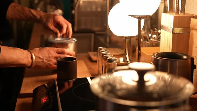 Cocoa making process on the wooden table in a cozy kitchen with a mood lighting. Chef Preparing cocoa drink. High-quality footage closeup cinematic 4k 10 bit. Pouring cocoa into cup.