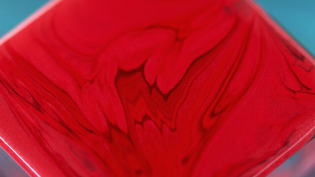 Liquid paint background. Smooth flow. Red burgundy dye mix with glitter particles abstract creative waves motion on square surface in captivating fantasy art.