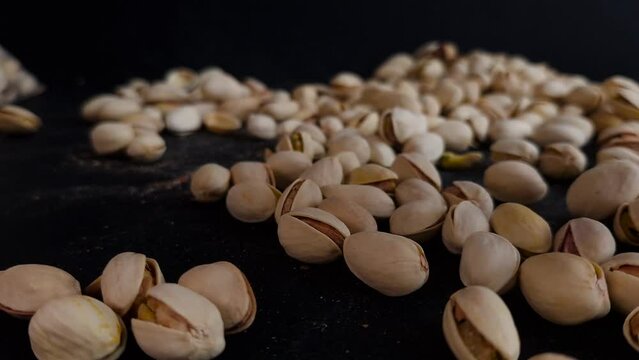 Slow Motion Shot of Flying Pistachios After Being Exploded on Black Gradient Background 