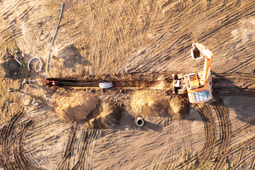 Drone photography of laying underground power line in the middle of the field during autumn morning