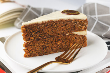 Slice of carrot cake on a white plate with a book in the background