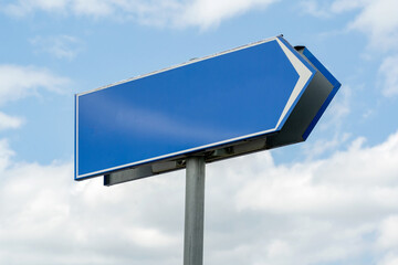 Empty blue highway sign with a directional arrow pointing right, set against a daytime sky with...