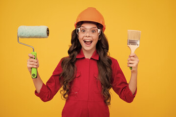 Child builder in hard hat helmet. Teenage girl painter with painting brush tool or paint roller....