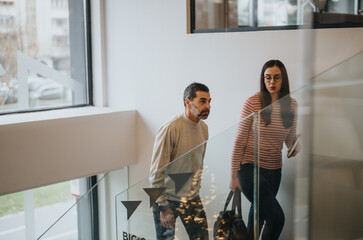 Fototapeta premium Two people in casual wear walking upstairs in a modern office building.