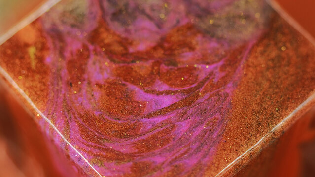 Glitter paint mix. Bokeh light. Blur bronze orange pink color sparkling texture ink liquid flow motion geometric cube shape abstract art background.