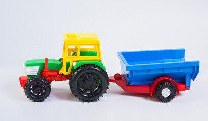 Toy plastic tractor with trailer on a white background.