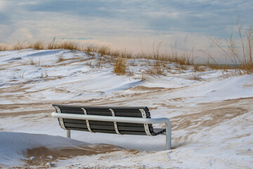 Frozen park bench on the icy shores of Lake Michigan, with a snow covered beach
