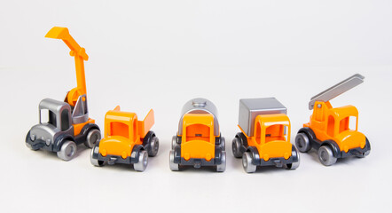 Construction vehicles lined up in a row. Multi-colored children's toys plastic trucks on a white background.