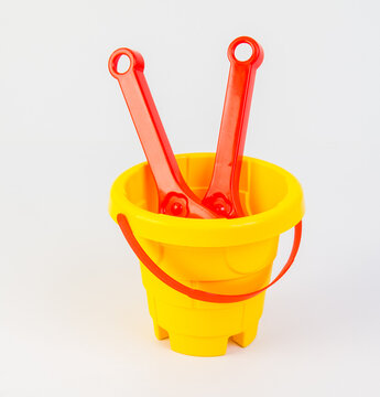 Children's toy bucket with shovels for playing in the sand on a white background.