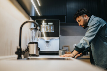 Focused man using modern coffee machine in sleek home kitchen.