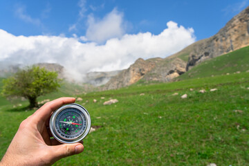 Travel compass in traveler's hand, mountain view