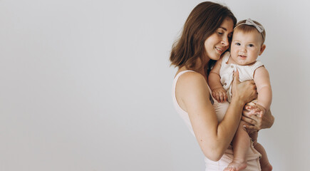 Happy young mother with her adorable baby girl on white background