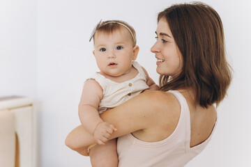 Happy mother with her beautiful little baby daughter in the bedroom on the bed
