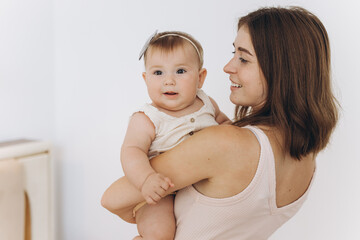Happy mother with her beautiful little baby daughter in the bedroom on the bed
