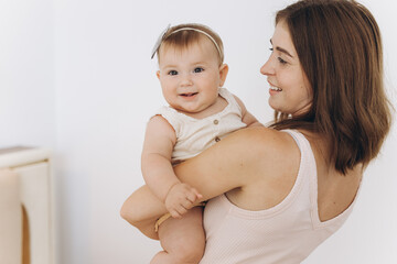 Happy mother with her beautiful little baby daughter in the bedroom on the bed