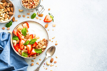Yogurt with granola and strawberries on white background. Healthy snack or breakfast. Top view with...