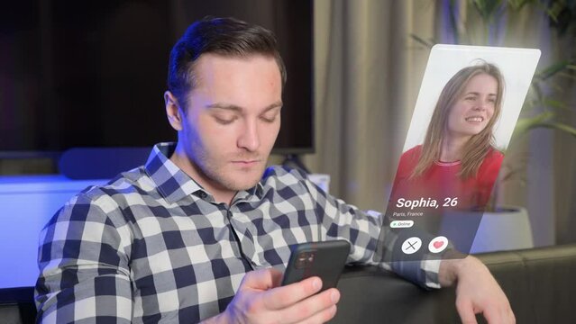Visual concept of a young man using a dating app on a smartphone and finding a match. Handsome man in modern home interior looking for woman on dating app