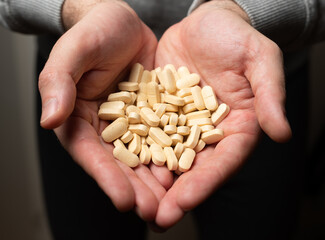 Male hands hold handful of white medicine tabs pills, concept of wellness