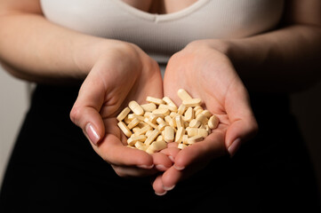 Female breast health awareness concept: woman hands hold handful of supplements for breast support and cancer prevention