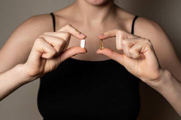 Woman hands hold two pills tabs medicine to kill pain, self help supplements concept, prescribed...