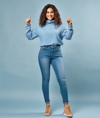 Smiling woman pointing finger, on blue background with copyspace