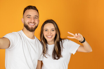 Fototapeta premium A happy young couple takes a selfie, with the man holding the camera and the woman giving a peace sign