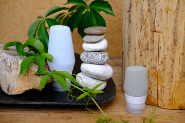 Round stones arranged in Zen tower pyramid, green plants, wooden elements and stylish bottle with...