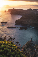 Male tourist enjoys marvellous sunrise from viewpoint on  cliff above seascape and along rugged...
