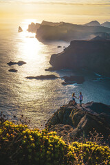 Young tourist couple stands on beautiful viewpoint on steep cliff overlooking the sea and the...