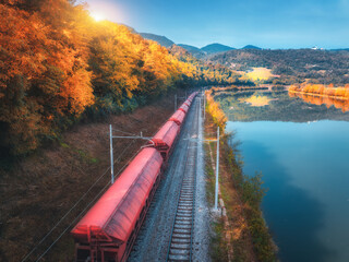 Aerial view of freight train moving near river in mountains