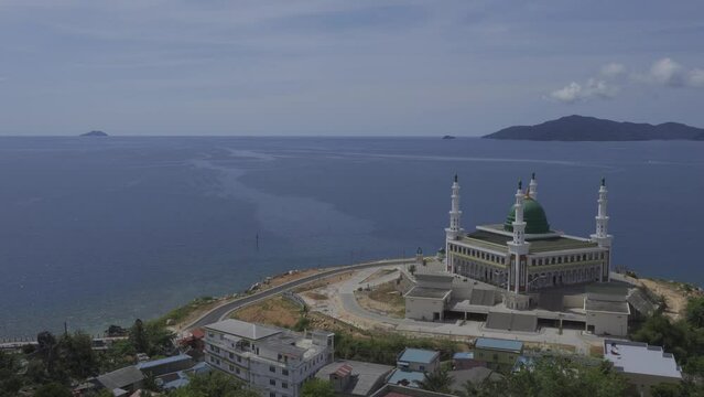 Aerial view of the magnificent beautiful Baitul Makmur Great Mosque, Tarempa. Mosque building by the sea with white paint and green dome. Eid al-Fitr Eid al-Adha Concept.