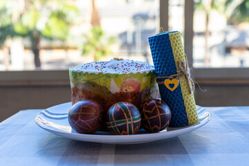 Traditional Ukrainian Easter cake (paska) with eggs (pysanky) and candle - obrazy, fototapety, plakaty