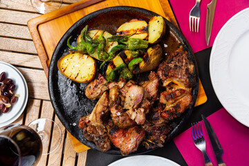 Pieces of appetizing roasted veal chop with side dish of baked potatoes and jalapenos pepper