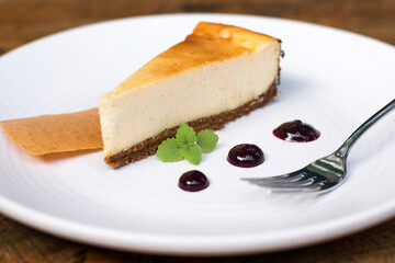 A slice of lime cheesecake on a white plate with a fork in a restaurant