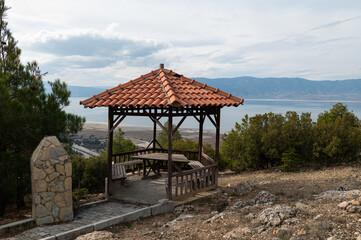 Picnic table with canopy and stone barbecue in the woods. Lake Burdur in the background.
