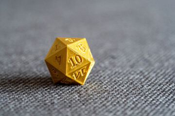 Golden 3D printed d20 RPG game dice on a bed object macro detail, extreme closeup, nobody. Playing tabletop RPG board games, larp and 3d printing accessories, geek nerd culture symbol abstract concept