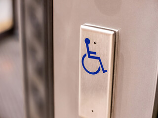 A metal button with a blue wheelchair symbol on it, object closeup, nobody. Accessibility for the...