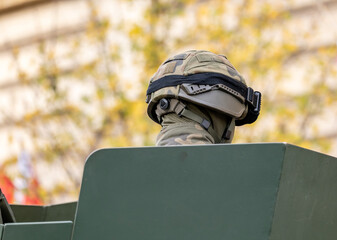 Anonymous military soldier in a camo camouflage uniform and a helmet sitting in an armored vehicle turret head closeup, back shot detail. Army, infantry conscription, professional armed groups concept